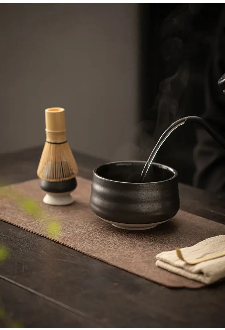 black matt bowl, bamboo whisk and holder of 4 piece ceramic matcha tea set with bamboo tea scoop