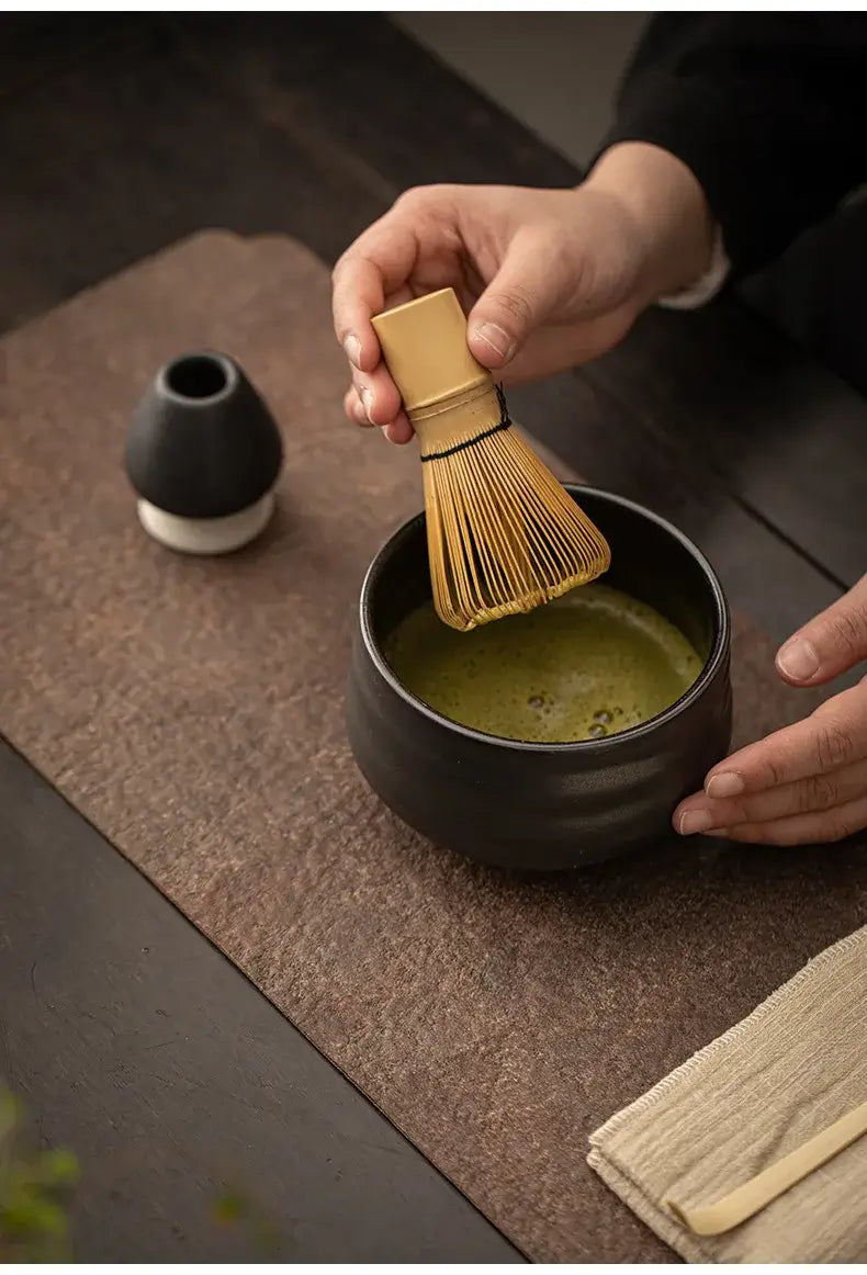black matt bowl, bamboo whisk and holder of 4 piece ceramic matcha tea set with bamboo tea scoop